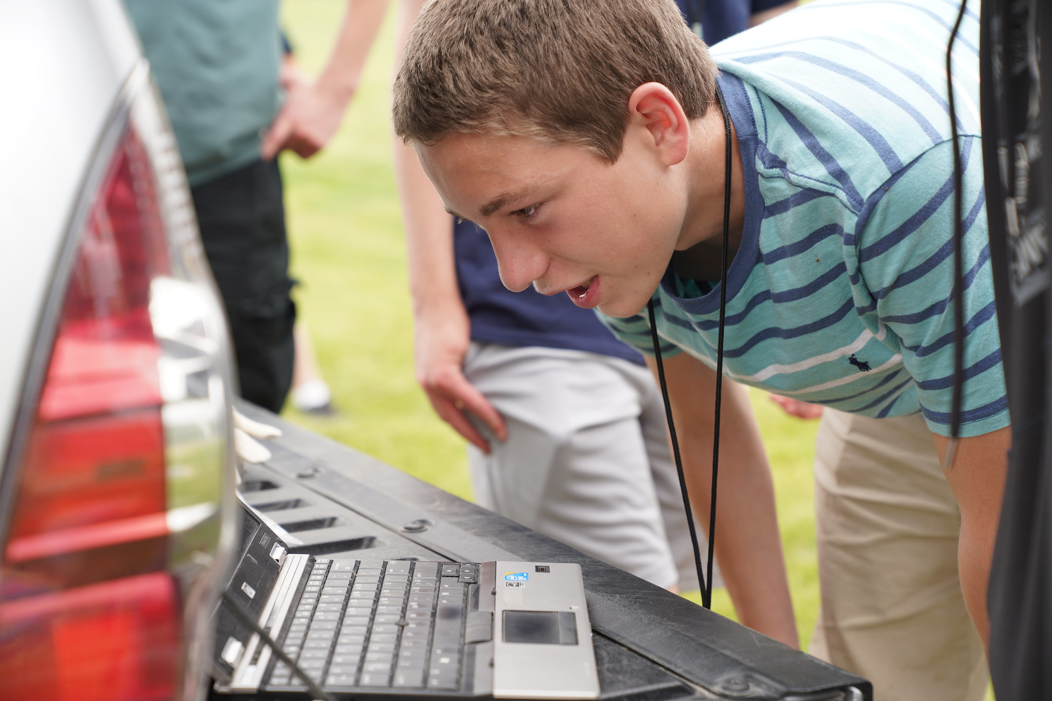 Student examining equipment connected to a laptop outdoors.