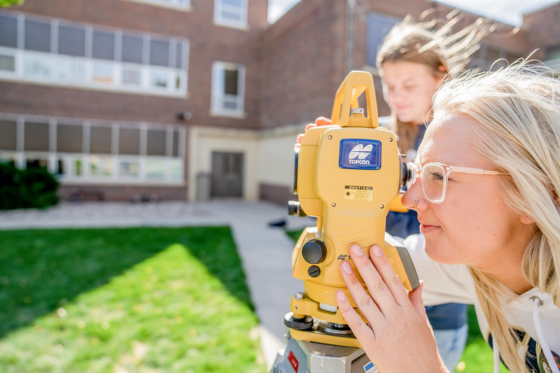 Students using a surveying instrument outdoors for hands-on fieldwork.