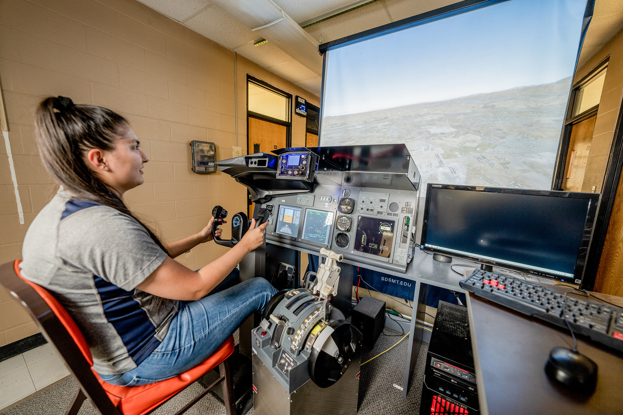 Student using a flight simulation setup with controls and monitors.