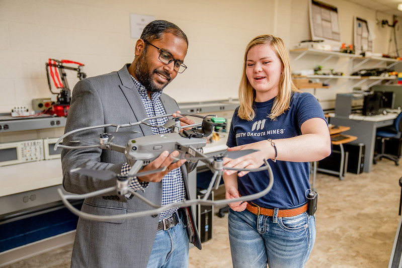 Student and instructor working with a drone in a laboratory setting.