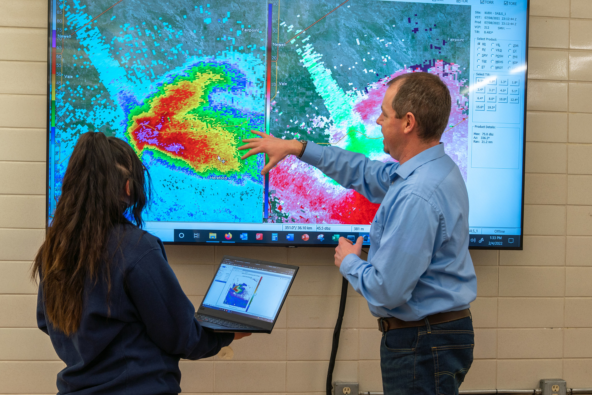 Instructor and student analyzing a weather radar display on a large screen.