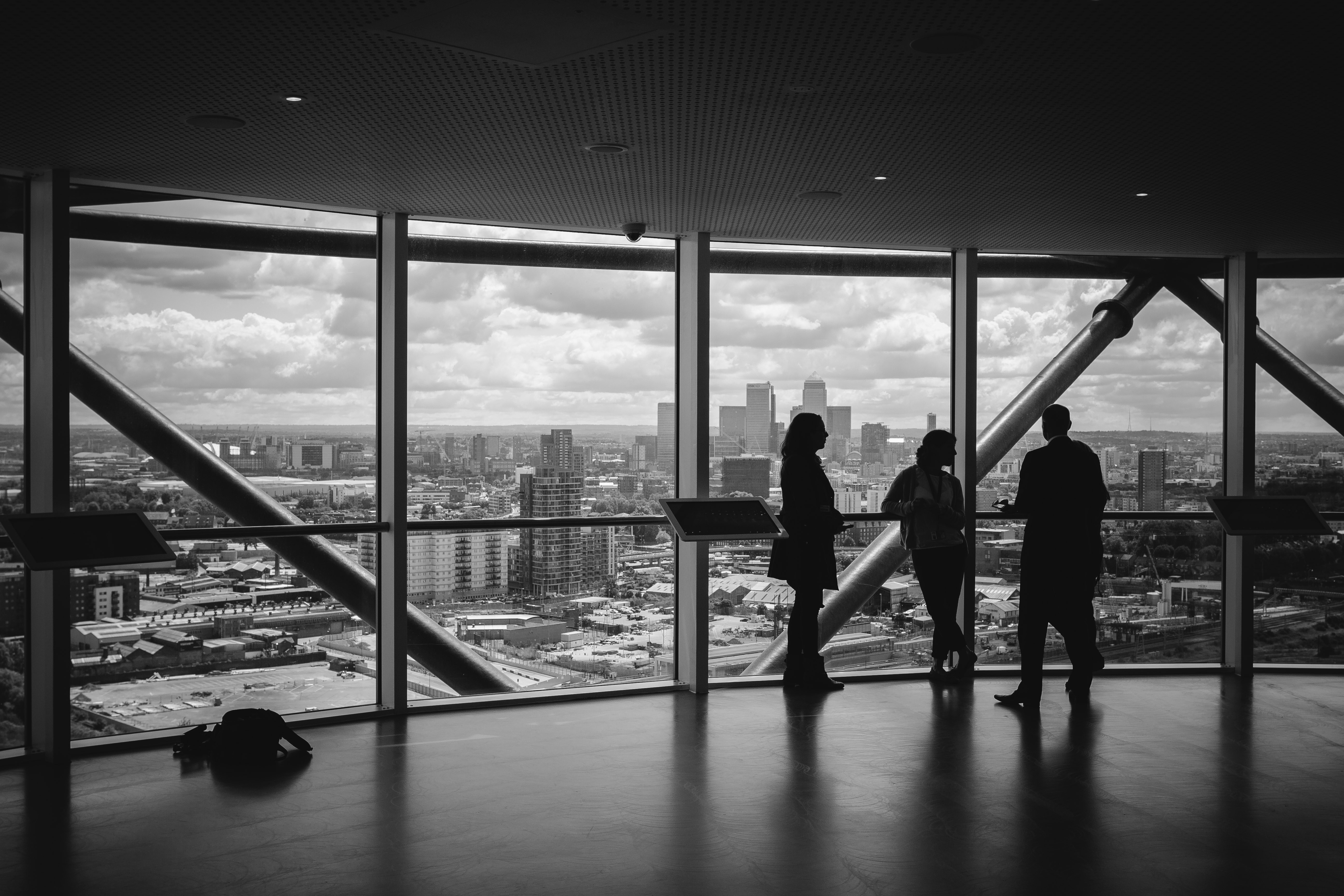 People viewing a cityscape through large glass window.
