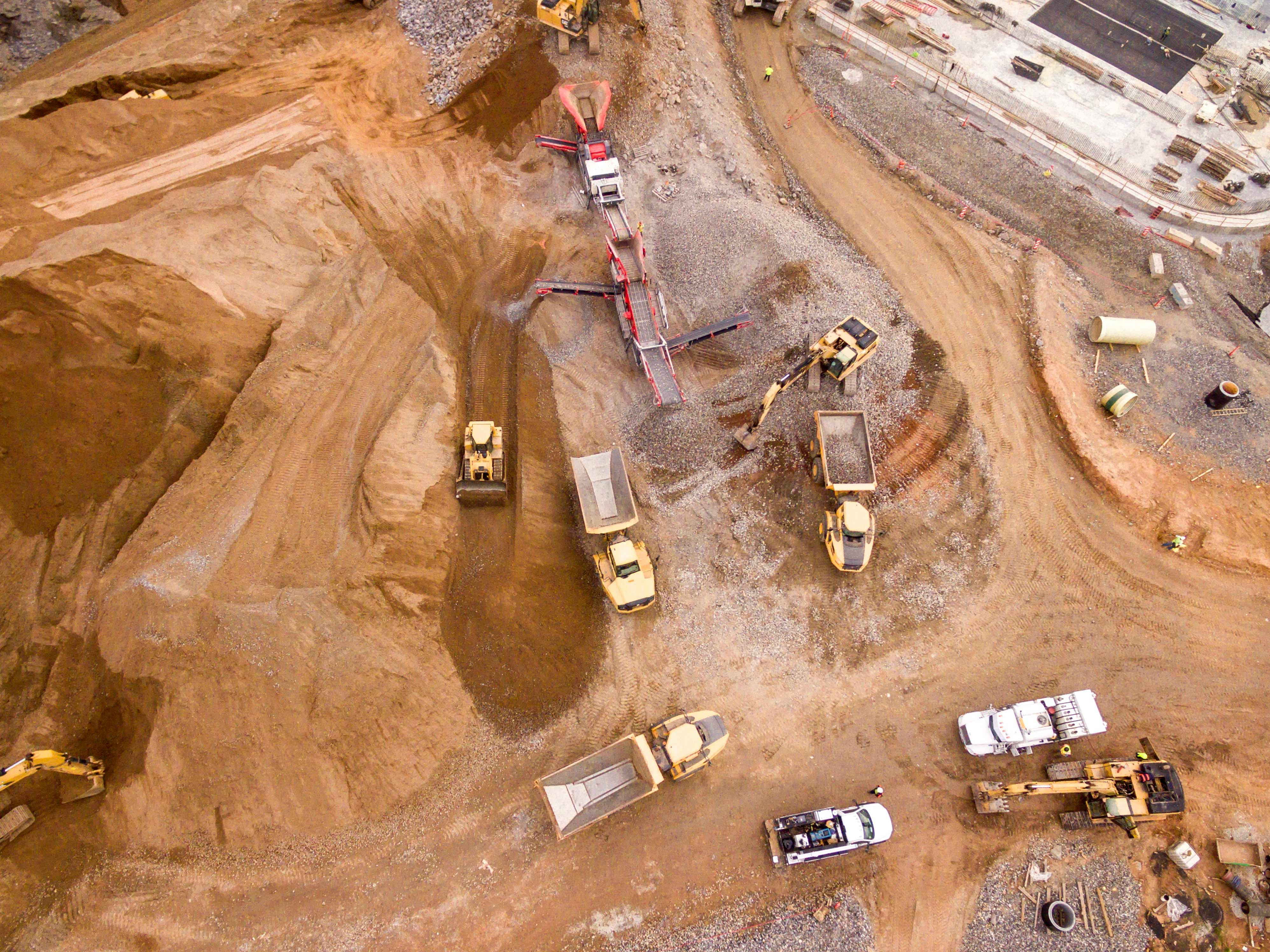 Aerial view of an ooen-pit mining site with heavy equipment and trucks.