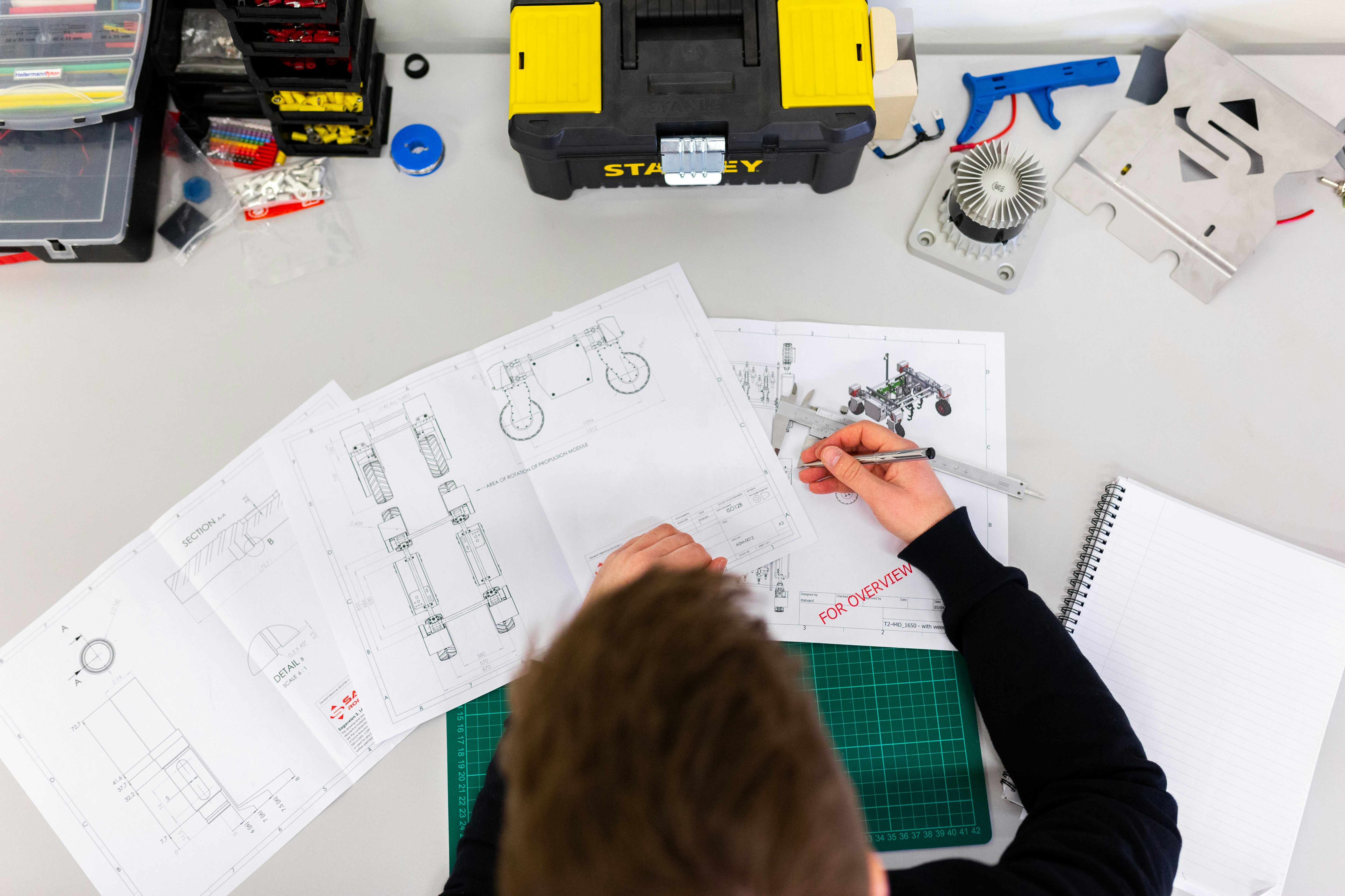 Student working on design sketches surrounded by tools and project materials.