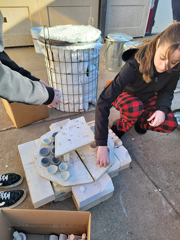 A Douglas High School student loads the raku kiln after designing a second iteration of glazes.