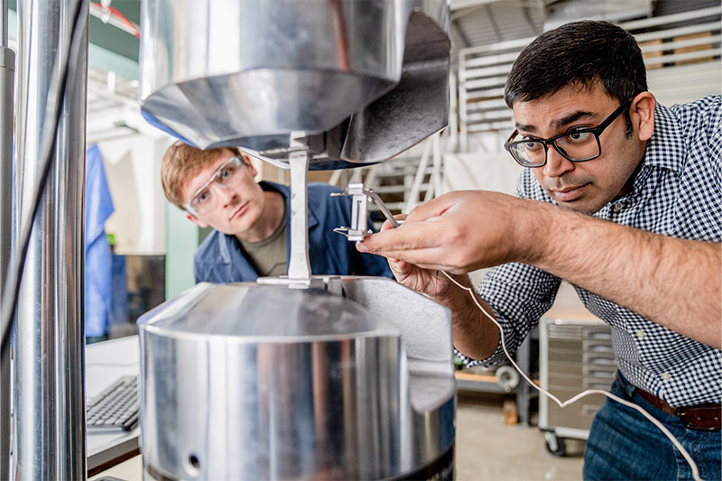 Researchers adjusting laboratory equipment.